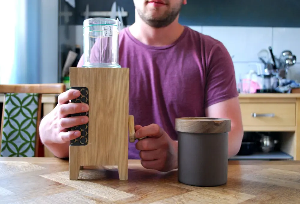 A young man using a semi-automated coffee grinder specifically
        designed to support psychological needs for competence, stimulation, and
        autonomy.